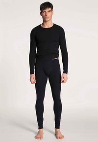 Zwarte thermische longsleeve shirt en leggings van rekbare stof, met een getailleerd ontwerp en een gladde textuur. Eenvoudige, minimalistische details.