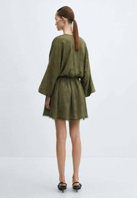 Robe vert olive avec une coupe décontractée, manches longues, taille élastique et bord en dentelle à l'ourlet. Texture douce, design arrive au genou.