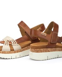 Sandali in pelle marrone con cinturini crema, piattaforma simile al sughero, cinturino alla caviglia regolabile e anelli decorativi sulla zona delle dita.