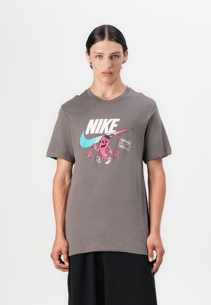Sivá bavlnená tričko s krátkymi rukávmi. Na prednej strane sa nachádza veľké mnohofarebné logo Nike a karikatúra. Dizajn s okrúhlym výstrihom.
