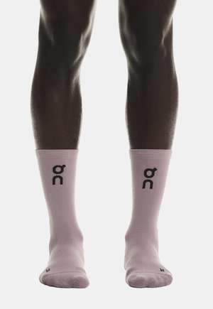 Legs wearing light pink mid-calf socks with black "on" brand logo facing forward on each sock.