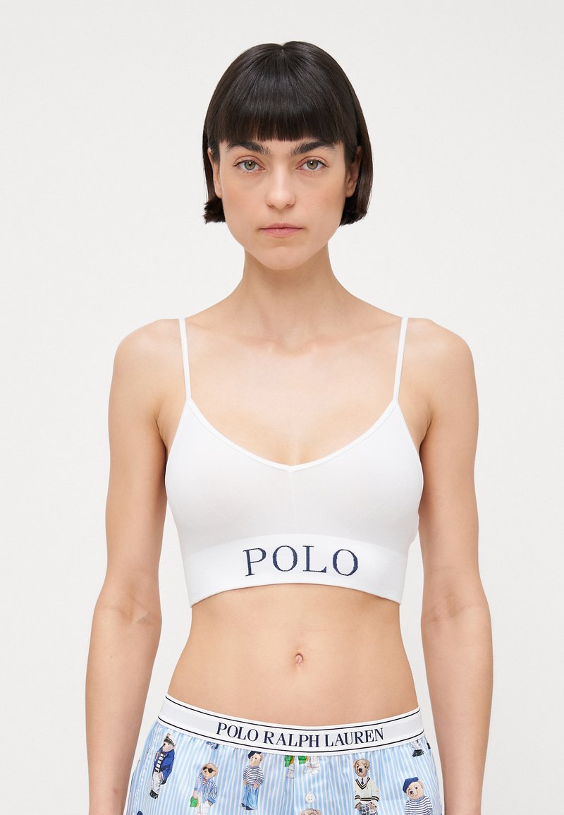 White ribbed bralette with thin straps, featuring a navy "POLO" logo on the band. Paired with blue patterned shorts.