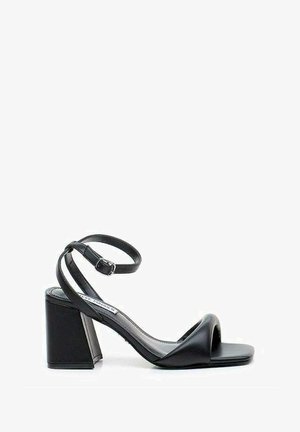 Sandal nero con tacco alto, rifinito in pelle liscia, punta aperta e tacco largo a blocco. Presenta una sottile cinturino alla caviglia con una fibbia in metallo.