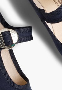 Tmavě modrá textilní bota s kulatou špičkou, elastickým páskem a stříbrnou kovovou přezkou. Měkká vnitřní podšívka a minimalistický design.