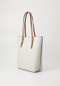 Sac fourre-tout en toile crème avec un motif logo subtil, poignées en cuir marron et quincaillerie dorée. Forme rectangulaire, fond plat.