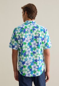 Camisa de manga corta con un patrón floral en azul, verde y blanco. Fabricada con tela ligera, tiene un ajuste holgado y un dobladillo curvado.