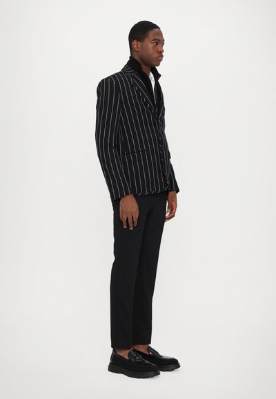 Black pinstriped blazer with a collar, paired with black trousers and platform loafers. Smooth texture, tailored design, structured fit.