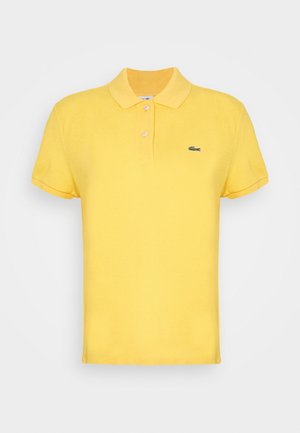 Polo jaune à manches courtes avec deux boutons blancs et un petit logo de crocodile vert sur la poitrine gauche.