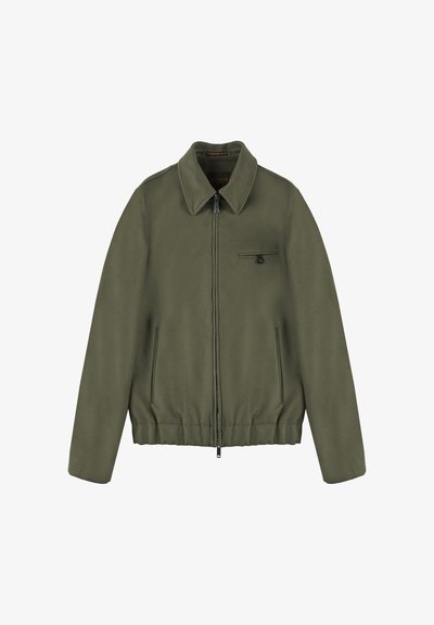 Olivgrüne Jacke aus weichem Stoff, mit durchgehendem Reißverschluss, großem Kragen, zwei Seitentaschen und einer kleinen Tasche mit Knopfdetail.