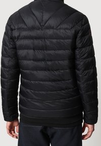 Sort pufferjakke med horisontal quiltning, høj krave og ribbede mansjetter. Glat, blank overflade med tætsiddende pasform og bemærkelsesværdig mærkepatch på ærmet.