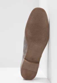 Chaussure en daim gris avec une semelle en caoutchouc marron lisse. Présente un motif antidérapant texturé sur la semelle et un design à profil bas. Taille 37 indiquée.
