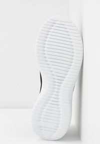 Mustat urheilukengät, joissa on ristikkäispintainen valkoinen kumipohja, joka sisältää aaltoilevan kuvion ja erottuvan kaarituen vakauden ja pidon tarjoamiseksi.