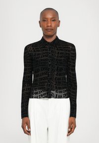 Black sheer button-up shirt featuring a textured design with repeated text patterns. Long sleeves and a pointed collar complete the look.