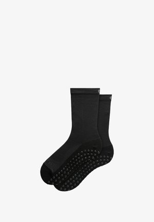 Calzini neri alla caviglia realizzati in tessuto testurizzato, con impugnature in gomma sulla soletta per migliorare la trazione e la stabilità.