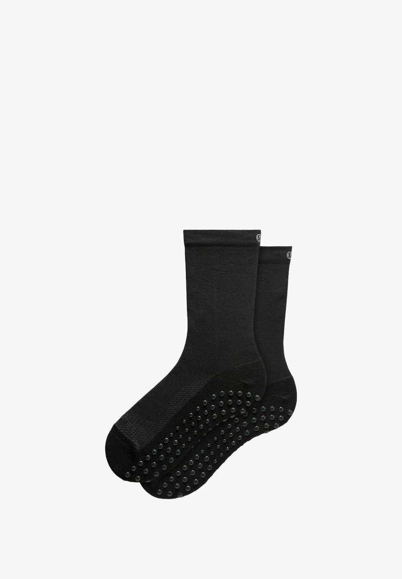 Calzini neri alla caviglia realizzati in tessuto testurizzato, con impugnature in gomma sulla soletta per migliorare la trazione e la stabilità.