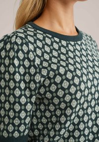 Pullover lavorato a maglia di colore verde scuro con motivo a diamante in verde chiaro e crema, caratterizzato da un collo rotondo e tessuto testurizzato.