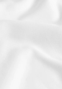 Tela blanca con una superficie lisa y ligeramente texturizada, que presenta pliegues y arrugas sutiles, indicando flexibilidad y suavidad.