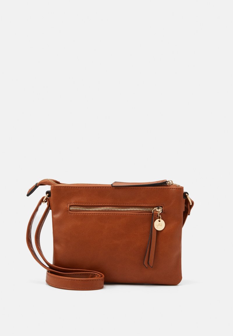 Borsa a tracolla in pelle marrone con tasca frontale con zip, hardware dorato, tracolla rimovibile e superficie liscia. Presenta un'etichetta decorativa.