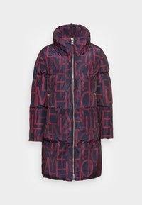 Navyblå vadderad jacka med hög krage och stora överlappande röda bokstäver, framdragkedja och dragkedjefickor på sidorna.