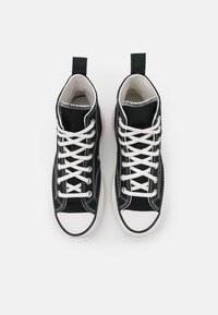 Baskets montantes en toile noire avec semelle et capuchon en caoutchouc blanc, dotées de lacets blancs, de détails de couture et d'une languette au talon.