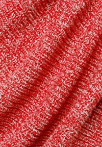 Tissu tricoté rouge et blanc avec un motif texturé, présentant des brins étroitement tissés et une surface douce, légèrement duveteuse.