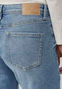 Jasnoniebieskie dżinsy z denimu z tylną kieszenią i beżową skórzaną metką z napisem "s.Oliver." Tkanina o fakturze i klasycznym kroju.