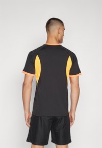 Herres kortærmet atletisk skjorte i sort med orange detaljer, lavet af let og åndbart stof og med en tætsiddende pasform.