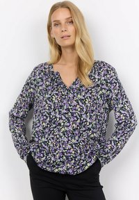 Long-sleeve blouse in dark fabric with a floral print featuring purple, green, and white. V-neckline and loose fit with a slightly gathered hem.