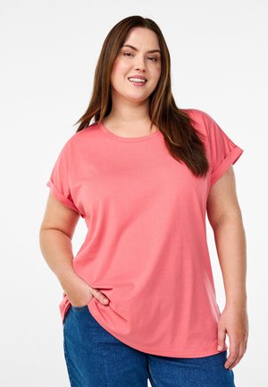Koraalkleurig T-shirt met korte mouwen, een ronde halslijn, een relaxte pasvorm en opgerolde mouwen, gecombineerd met blauwe denim jeans. Smalle katoenstructuur.