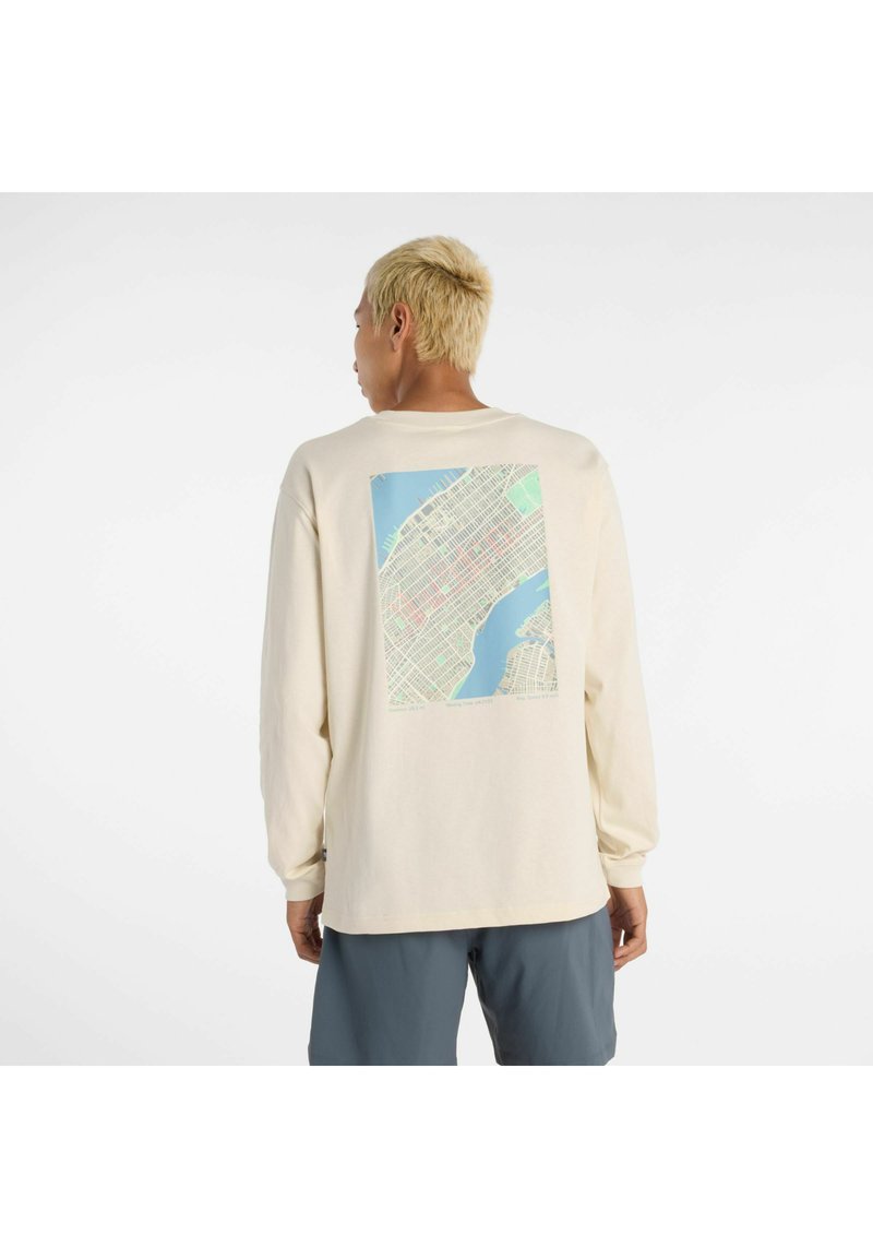 Camiseta de manga larga en color crema con un diseño de mapa en la parte posterior en tonos de azul y verde, con un corte relajado y puños acanalados.