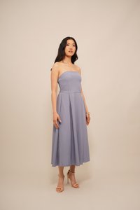 Brezramna, dolga obleka iz svetle sivke z gubami. Gladka tekstura, oprijet korzet in skromen razširitev kroga.