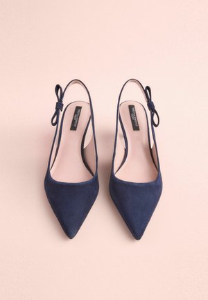 Laivyno mėlynos zomšos slingback kulniukai su smailiais pirštais, turintys ploną dirželį ir kaspiną, elegantiškas dizainas ir lygus vidinis pamušalas.