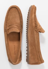 Mocassini slip-on in suede marrone con design cucito e suola in gomma dotata di piccoli grip rotondi; interno liscio e logo impresso sulla soletta.