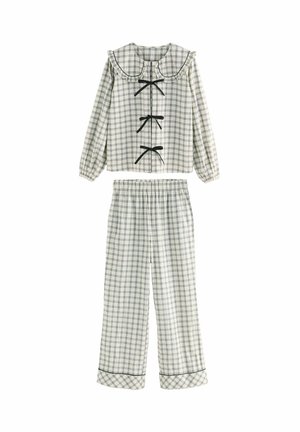 Checked pajamas set in cream and navy. Features a ruffled collar, three black bows, and elastic waist pants with a patterned hem.
