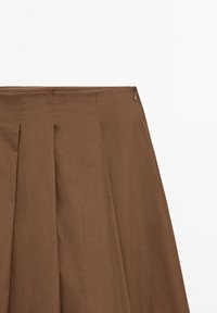 Jupe marron trapèze avec plis et fermeture éclair latérale sur fond blanc