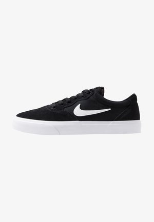 Schwarze Wildleder-Sneaker mit weißen Gummisohlen, versehen mit einem weißen Nike-Logo an der Seite, runder Zehenpartie und klassischem Schnürdesign.