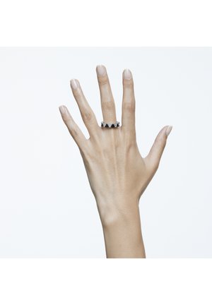Silberner Ring mit einem geometrischen, gewellten Design, das abwechselnd schwarze und silberne Akzente aufweist. Tragen an einer Hand mit sichtbaren, natürlichen Nägeln.