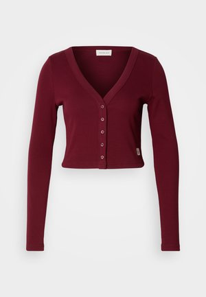 Burgundská skrátená cardigan s V-výstrihom, dlhými rukávmi a siedmimi prednými gombíkmi. Vyrobená z elastického materiálu, s priliehavým strihom.