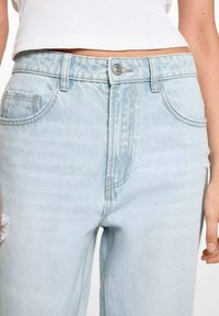 Jeans in denim blu chiaro con vita alta, design a cinque tasche, leggero sbiadimento e orlo sfilacciato sul lato sinistro. Chiusura a bottone incisa.