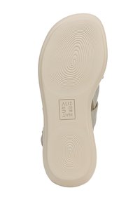 Soletta beige con fondo in gomma testurizzata caratterizzata da linee ondulate e logo al centro; i materiali includono cinghie in tessuto e fibbia regolabile.