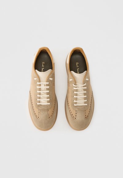 Baskets en daim beige avec détails perforés, lacets crème et semelle en caoutchouc tan. Accents en cuir lisse au talon.