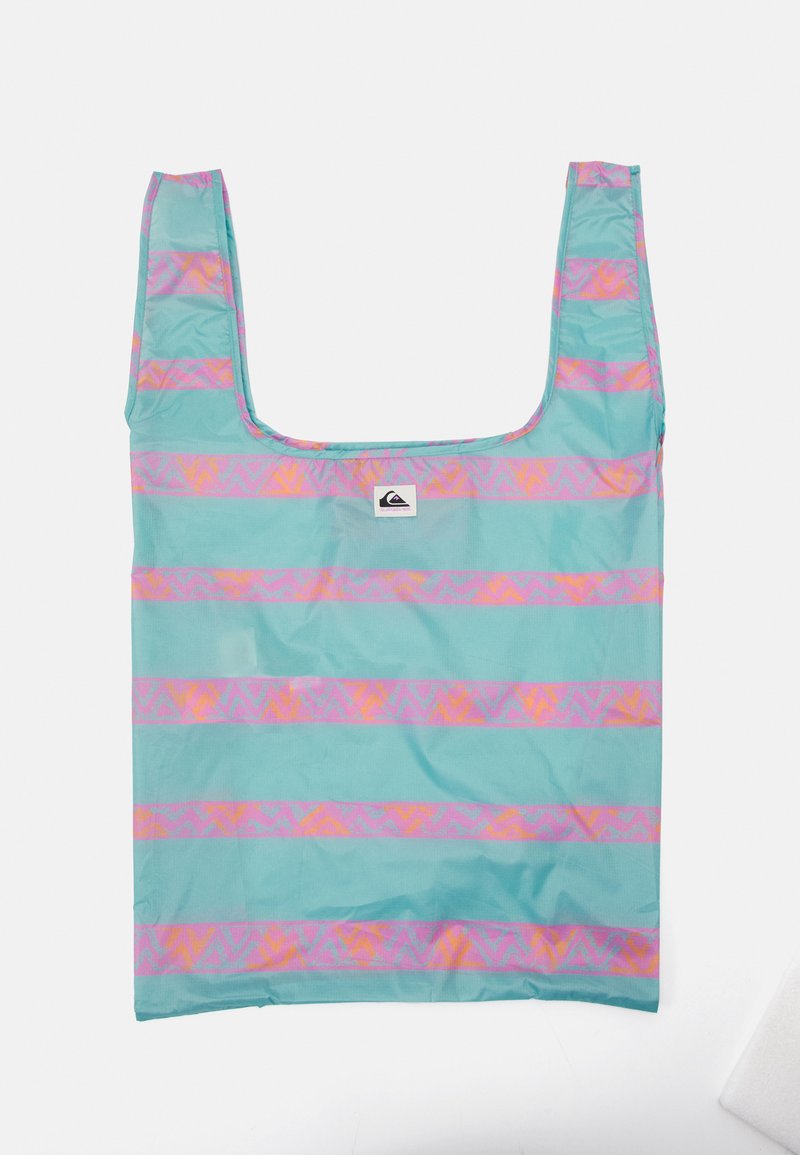 Bolsa de tote reutilizable en turquesa con rayas horizontales de patrones geométricos en rosa y naranja. Presenta un asa de corte cuadrado y una etiqueta de logo.
