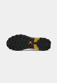Suela de zapatilla atlética en goma negra con patrones de rodadura definidos, con un acento amarillo y naranja para mejorar el agarre y la tracción.