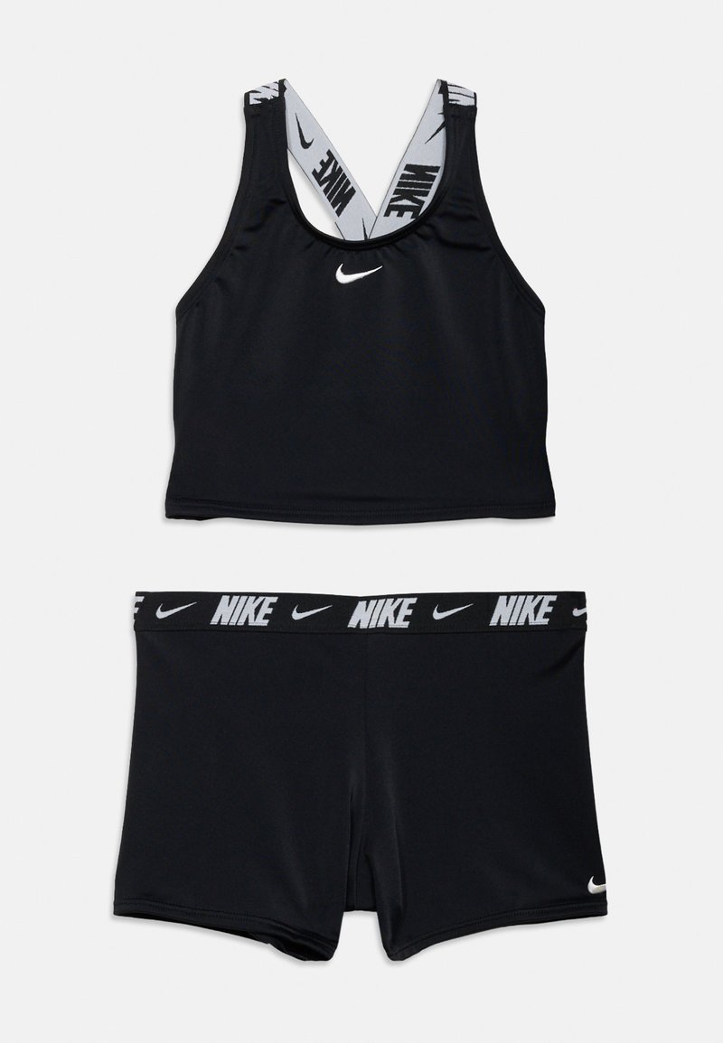 Haut court de sport Nike noir avec logo blanc et short noir assorti avec une ceinture à logo Nike et un petit logo blanc sur la jambe.