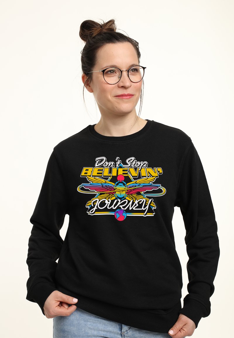 Felpa nera con una grafica colorata che presenta la scritta "Don't Stop Believin'" e un'immagine stilizzata di un uccello in colori vivaci.