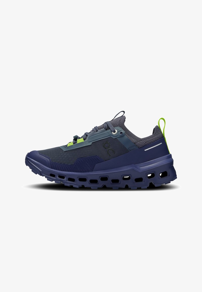 Chaussure de sport bleu foncé et grise avec dessus en mesh, semelle épaisse et robuste avec découpes, languette lime verte et design à lacets.