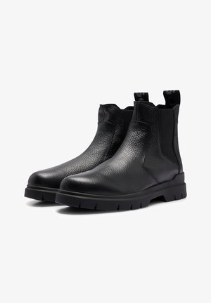 Botas chelsea de cuero negro con acabado texturizado, paneles laterales elásticos y tiradores. Suela gruesa de goma con patrón de banda de rodadura para mayor agarre.