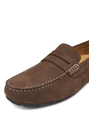 Mocasines de ante marrón con punta redondeada, con costuras decorativas y un detalle de cuero en la parte superior. Superficie texturizada y suela de goma.