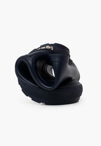 Chaussure noire flexible avec un design incurvé, semelle en caoutchouc texturée et un logo proéminent sur la partie supérieure. Matériau mou et moulé.