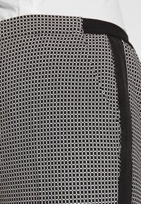 Svart och vit mönstrad tyg med rutmönster. Har en slät yta och svarta accenter längs kanterna.